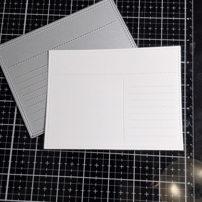A piece of white cardstock has been die cut with the A2 postcard die. 